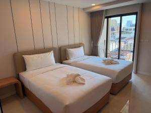 two beds in a hotel room with towels on them at Aston Hotel Pattaya in Pattaya +32 photos
