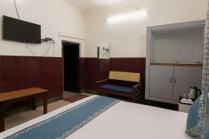 ein Schlafzimmer mit einem Bett, einem Fernseher und einem Stuhl in der Unterkunft The Ayodhya Ji Palace in Ayodhya