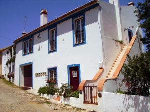 - un bâtiment blanc avec des fenêtres bleues et un escalier dans l'établissement Turimenha, à Marvão