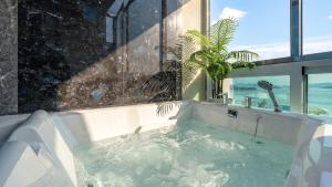 a bathroom with a bath tub with a large window at Yeosu Hemiswi SPA Pension in Yeosu