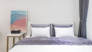 a bedroom with a bed with purple sheets and pillows at Yeosu Hemiswi SPA Pension in Yeosu
