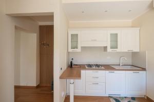 een keuken met witte kasten en een spoelbak bij Gioia Apartment in Sabaudia +2 foto's