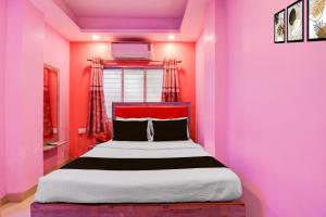 een slaapkamer met een bed met een roze muur bij Hotel O Golden Star in Ballygunge