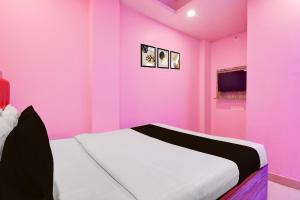 een roze slaapkamer met een wit bed en een televisie bij Hotel O Golden Star in Ballygunge