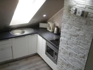 a kitchen with white cabinets and a stone wall at Ferienunterkunft Grüner Weg in Ueckermünde