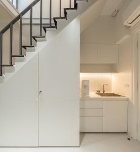 a kitchen with white cabinets and a staircase at Bedd Hostel in Bangkok