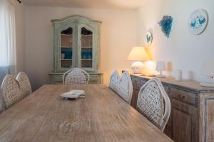 een eetkamer met een houten tafel en stoelen bij Appartamento Baia Caddinas fronte mare in Golfo Aranci