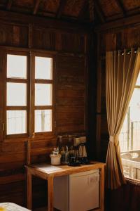 eine Küche mit einem Tisch, 2 Fenstern und einem Kühlschrank in der Unterkunft Nauna Villa Bali in Ubud