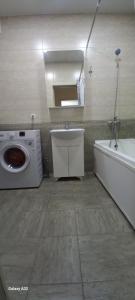 een badkamer met een wasmachine, een wastafel en een bad bij Апартаменты in Tasjkent