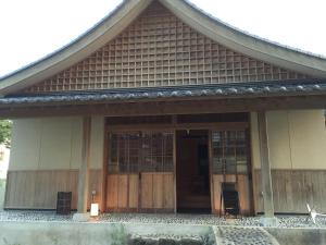 a house with a large wooden door and a porch at Hotel Kadoman in Aso