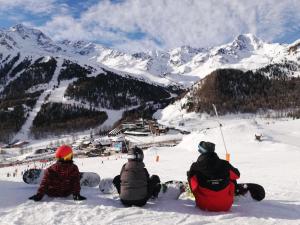 three people sitting on top of a snow covered mountain at Sporthotel Kurzras in Maso Corto