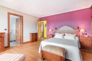 una camera con un grande letto e una parete viola di El Pongallin a Sevares
