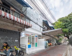 a man sitting on a bench in front of a building at Bedd Hostel in Bangkok