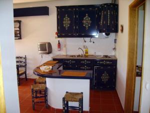 a kitchen with black cabinets and a sink and chairs at Turimenha in Marvão