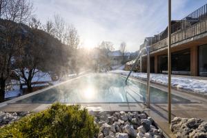 - une piscine avec une fontaine dans la neige dans l'établissement Les Dolomites Mountain Lodges, à San Martino in Badia