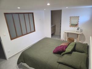 een slaapkamer met een groen bed en een tafel bij Les Noisetiers appartement in Saint-Just-Malmont