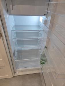 een koelkast met een open deur met een lege plank bij Les Noisetiers appartement in Saint-Just-Malmont