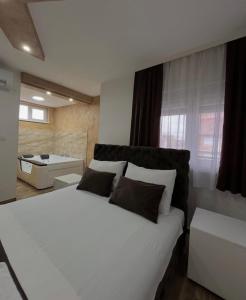 een slaapkamer met een groot wit bed en een badkamer bij Sobe i Apartmani Casa Mia in Pećinci