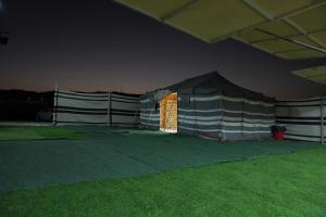 een tent met een lichtje in een veld 's nachts bij Sanmar camp in Ḑibāb