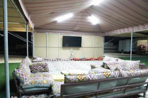 een woonkamer met banken en een projectiescherm bij Sanmar camp in Ḑibāb