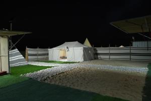 een witte tent in een veld 's nachts bij Sanmar camp in Ḑibāb