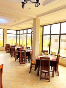 a dining room with tables and chairs and windows at Rejis Hotel in Dodoma
