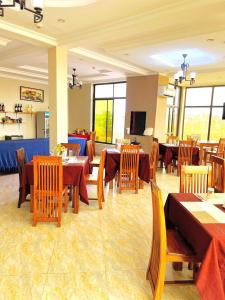 a restaurant with wooden tables and chairs and tablesearcher at Rejis Hotel in Dodoma