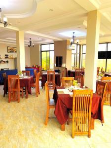 a restaurant with wooden tables and chairs and tablesearcher at Rejis Hotel in Dodoma +46 photos