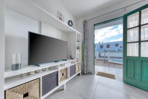 a living room with a tv and a sliding glass door at Carpe Diem Apartment - Pool view By Lanzarote Vacation Homes in Puerto del Carmen
