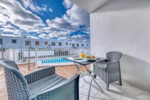 een terras met een tafel en stoelen en een zwembad bij Carpe Diem - Shared Pool By Lanzarote Vacation Homes in Puerto del Carmen