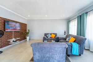 un soggiorno con 2 sedie e un muro di mattoni di KhayaLethu Vic Falls 2 a Victoria Falls