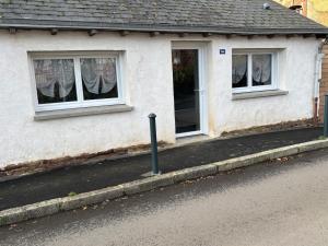 a white house with two windows and a sidewalk at Charmante maison in Pleumeleuc