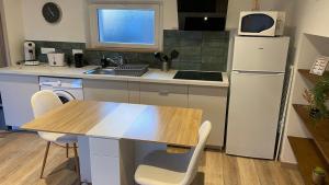 a kitchen with a wooden table and a refrigerator at Charmante maison in Pleumeleuc