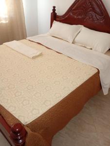 a bed with a wooden headboard and white sheets at The Lakeside Beach Hotel in Busia