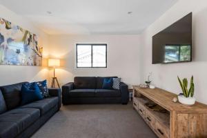 een woonkamer met een bank en een tv bij Narrawallee Oasis in Narrawallee