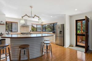 een keuken met een bar met krukken en een koelkast bij Narrawallee Oasis in Narrawallee