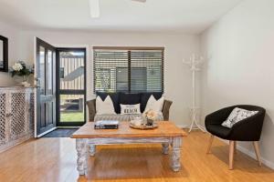 een woonkamer met een salontafel en een stoel bij Narrawallee Oasis in Narrawallee +14 foto's