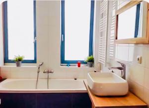 a bathroom with a tub and a sink and windows at Canal House - Homestay in Alkmaar +29 photos