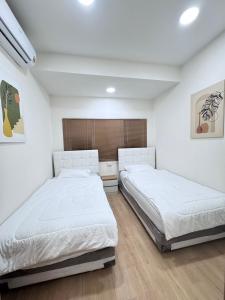 twee bedden in een slaapkamer met witte muren en houten vloeren bij Sun Sun Hostel in Pai