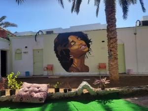 een muurschildering van een vrouw aan de zijkant van een gebouw bij Badya Camp بادية كامب in Dahab +6 foto's