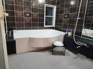 een badkuip in een badkamer met zwarte tegels bij ホテルメイプル in Odate
