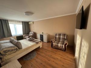 een slaapkamer met een bed en 2 stoelen. bij Panorama Spa Apartment in Berehove