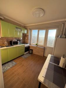 een keuken met groene kasten en een houten vloer bij Panorama Spa Apartment in Berehove +3 foto's