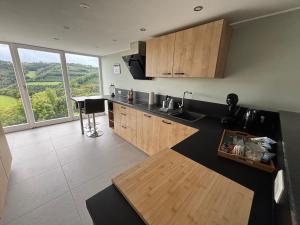 a kitchen with wooden cabinets and a large window at Apartment with panoramic view in Lipperscheid