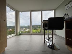 a office with a desk and a chair in a room with windows at Apartment with panoramic view in Lipperscheid