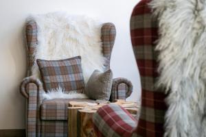 a living room with a plaid chair and a rug at Grifone Dolomiti Residences in Arabba