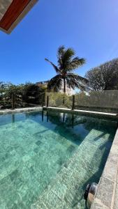 a swimming pool with a palm tree in the background at High Standard Two Bedroom Apartment Private Pool Frances Beach Garden 209 in Marechal Deodoro