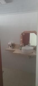 een badkamer met een witte wastafel en een spiegel bij Cantinho da Dê in Anchieta