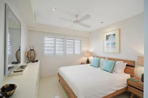 een witte slaapkamer met een groot bed en een raam bij Coastal Chic with Heated Pool Quiet Location in Sunshine Beach