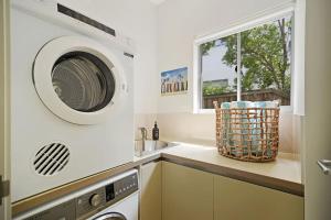 een keuken met een wasmachine en een wastafel bij Coastal Chic with Heated Pool Quiet Location in Sunshine Beach